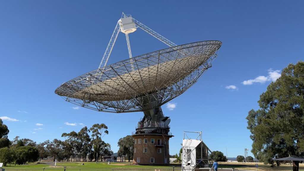 a large windmill in a field with Karl G. Jansky Very Large Array in the background